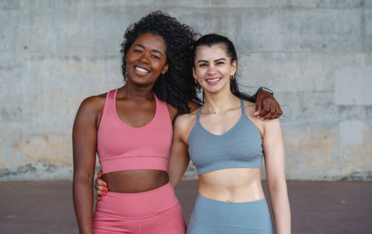 Moda fitness no empoderamento feminino: mais do que vestuário | Duas mulheres abraçadas vestindo roupas fitness